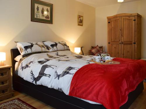 a bedroom with a bed with a red blanket at Crossburn Hideaway in Helensburgh