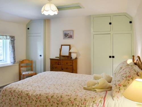 a bedroom with a bed and a dresser and a mirror at Yew Tree Cottage in Arford