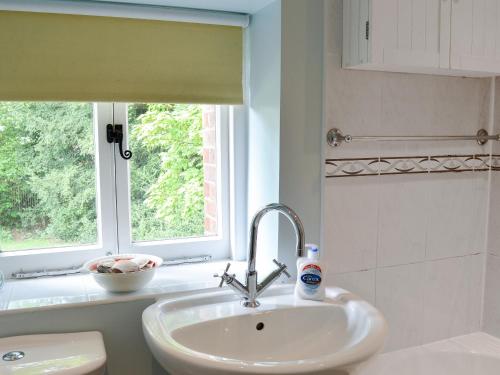 baño con lavabo y ventana en Yew Tree Cottage en Arford