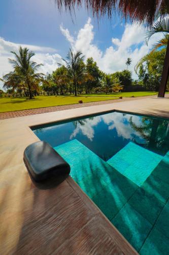 a swimming pool with a black ottoman sitting next to it at Bahay Tatu in Pôrto de Pedras