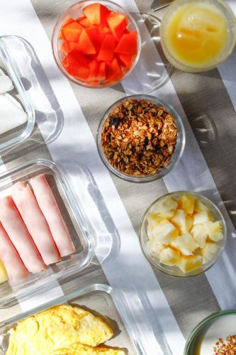a table topped with plastic containers filled with different foods at Bahay Tatu in Pôrto de Pedras
