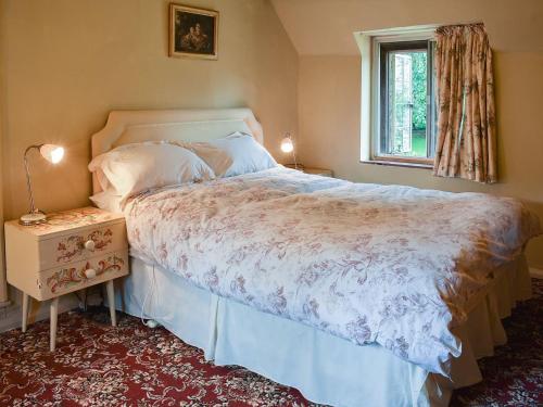 a bedroom with a large bed and a window at Cerne Abbey Cottage in Cerne Abbas