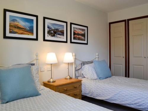 um quarto com 2 camas e 2 candeeiros e fotografias na parede em Melbreak em Lorton