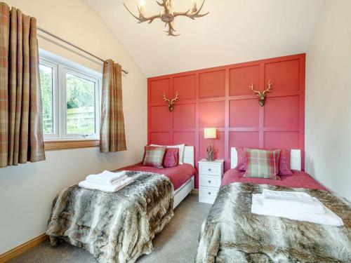 two beds in a room with red walls at Appletree Lodge in Minishant