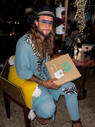 a man sitting in a chair holding a box at Xkeban Tulum Adults Only in Tulum