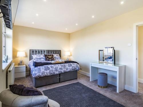 a bedroom with a bed and a chair and a table at The Laurels in Clenchwarton