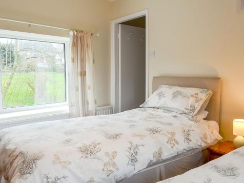 a bedroom with a bed and a window at The White Cottage in Furness Vale