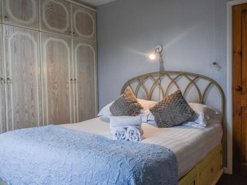 a bedroom with a bed with blue sheets and pillows at Holly Cottage in Brotton