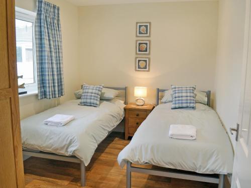 2 camas individuales en una habitación con ventana en Tegen, en Tywardreath