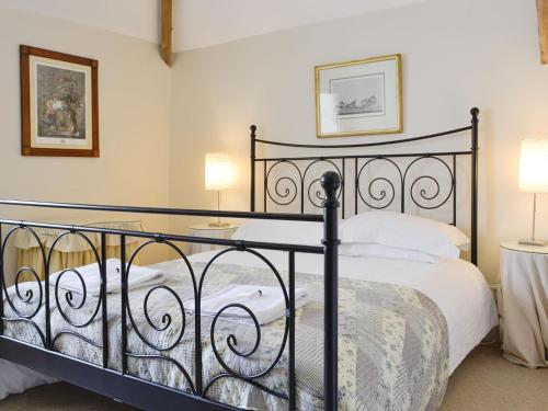 a bedroom with a black bed with white pillows at Crogen Coach House - Oqr in Llandrillo