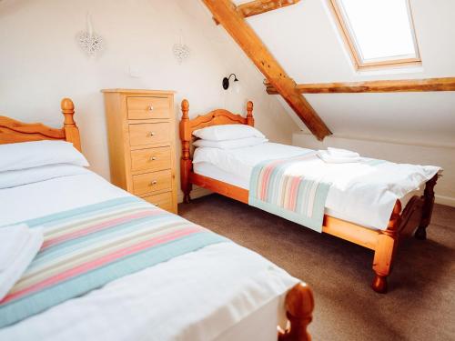 a bedroom with two beds and a dresser in it at Goose Cottage- Uk6737 in Lydstep