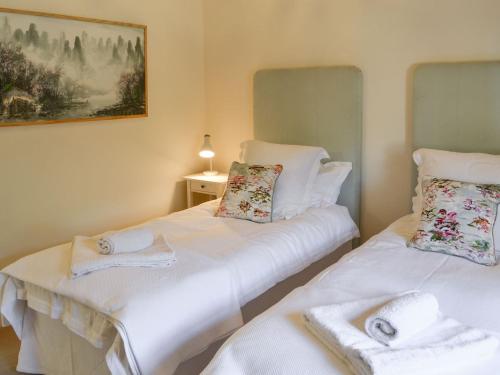 two beds in a room with white sheets and towels at The Stables in Berwick Hill