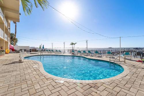 a swimming pool with chairs and the ocean in the background at Beso del Sol Resort in Dunedin - Perfect Location & Relaxation! in Dunedin
