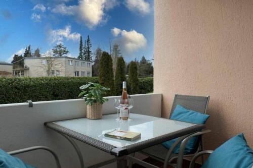 a table with a bottle and a candle on a balcony at Moderne Ferienwohnung Grömitz mit Garten/Terrasse in Grömitz