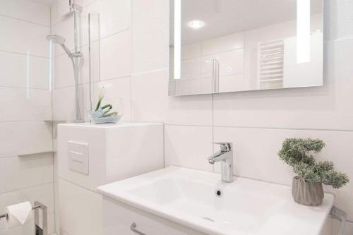 Baño blanco con lavabo y espejo en Moderne Ferienwohnung Grömitz mit Garten/Terrasse, en Grömitz