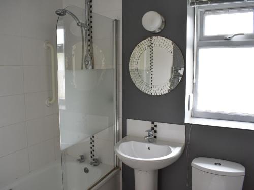 een badkamer met een wastafel, een toilet en een spiegel bij Mussel Cottage in Middleton-on-Sea