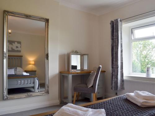 a bedroom with a mirror and a bed and a chair at Ling Farm Cottage in Holmewood