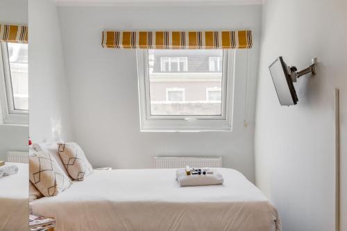 Habitación blanca con cama y ventana en 1 Lexham Gardens Hotel, en Londres