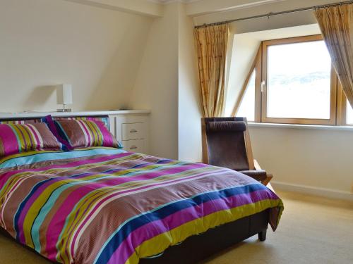 a bedroom with a colorful bed and a window at Waterside in Tighnabruaich