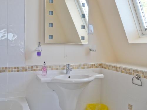 een witte badkamer met een wastafel en een spiegel bij Waterside in Tighnabruaich