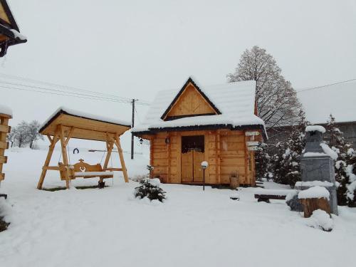 a wooden cabin in the snow with a swing at Domek u Śpiewoka 1 in Maruszyna