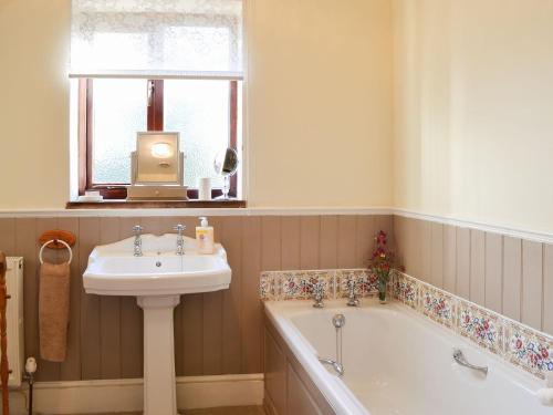 a bathroom with a sink and a bath tub and a sink at Acorn Barn in Foggathorpe