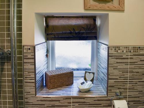 baño con ventana con lavabo y ducha en The Carriage House, en Watermillock