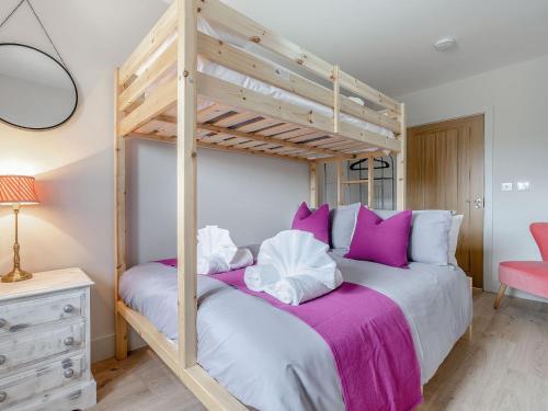 een slaapkamer met een houten stapelbed met paarse kussens bij The Stables in Stanhope