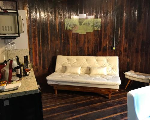 Sofá blanco en una habitación con pared de madera en Villa Vinicolla Hospedagem Conceito, en Bento Gonçalves