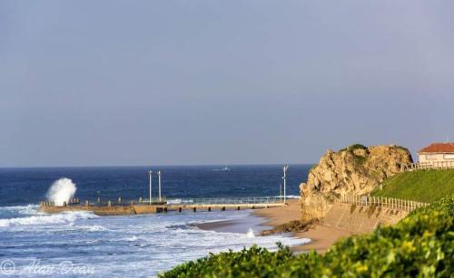 a beach with waves and a pier in the ocean at Rose Holiday Home in Durban