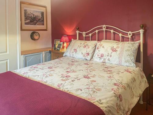 a bedroom with a bed with a floral bedspread at Mays Cottage in Melbury Abbas