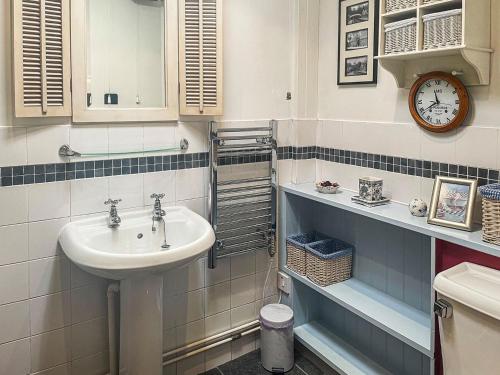 a bathroom with a sink and a clock on the wall at Mays Cottage in Melbury Abbas