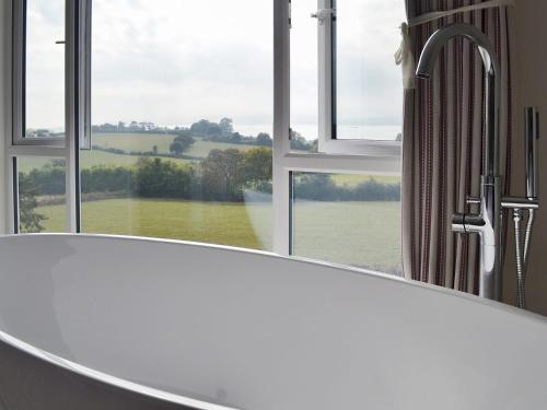 a bath tub in front of a window with a view at Estuary View in Lympstone