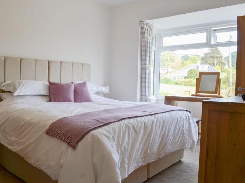 a bedroom with a large bed and a window at Estuary View in Lympstone