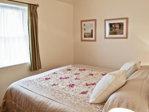 Un dormitorio con una cama con una manta floral. en Jasmine Cottage - W41461, en Sturminster Newton