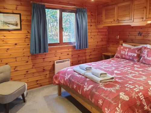 a bedroom with a bed in a log cabin at Burnside Alderwood in Garboldisham