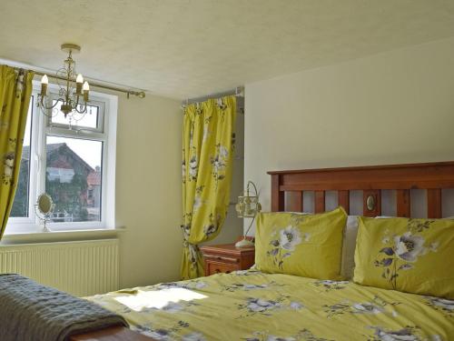 a bedroom with a bed and a window with yellow curtains at Florence Cottage in Pakefield