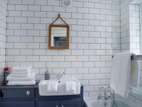 a white bathroom with a sink and a mirror at Florence Cottage in Pakefield