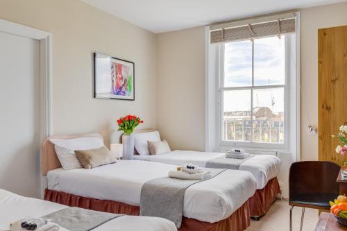 sypialnia z dwoma łóżkami i oknem w obiekcie 1 Lexham Gardens Hotel w Londynie