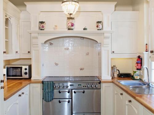een keuken met witte kasten en een roestvrijstalen kachel bij Luppincott Chambers - Hpps in Bideford