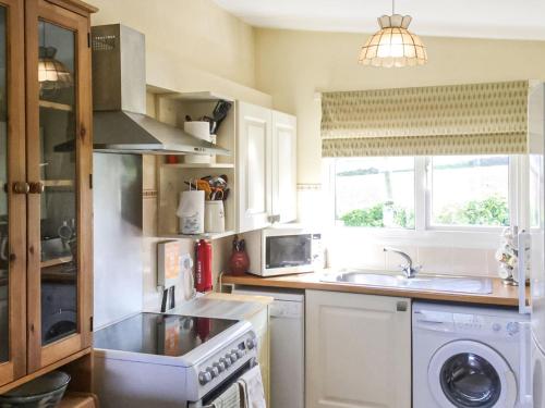 a kitchen with a sink and a stove top oven at Foxgloves Bungalow Uk39618 in Welcombe