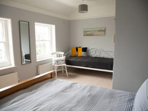 a bedroom with a bed and a mirror and a chair at Pebble Cottage in Felpham