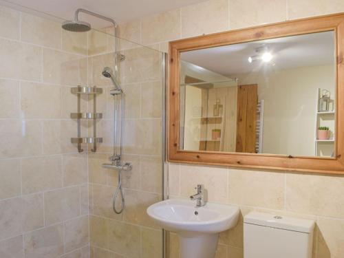 a bathroom with a sink and a shower with a mirror at Y Glowty in Maenclochog