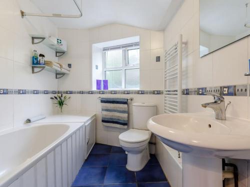 a white bathroom with a sink and a toilet and a tub at The Cottage in Wells