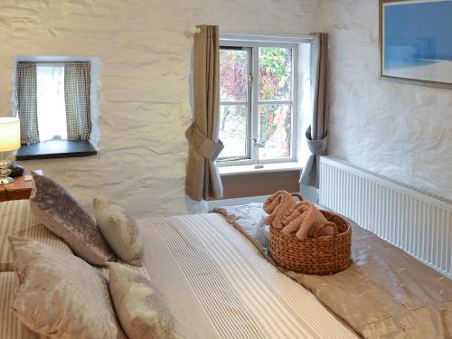 a bedroom with a bed with a basket and a window at Hollies Cottage - 27593 in Perranzabuloe