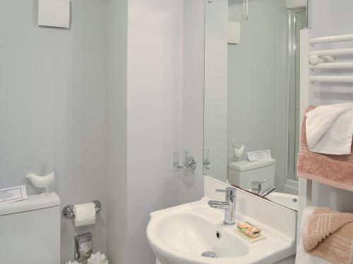 Baño blanco con lavabo y espejo en Hollies Cottage - 27593 en Perranzabuloe