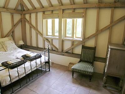 um quarto com uma cama e uma cadeira num quarto em The Old Packhouse em Steyning