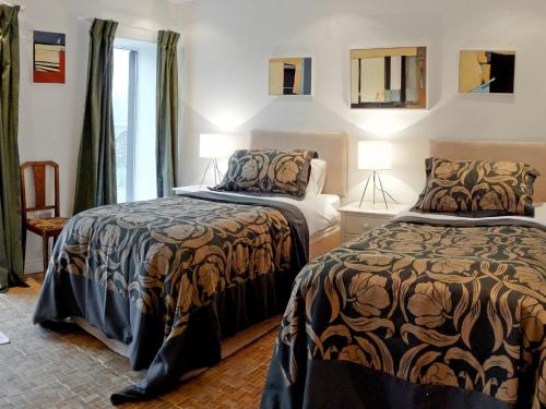 a bedroom with two beds and a window at The Old Pool House in Charlton Abbots