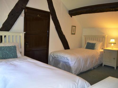 a bedroom with two beds in a room with beams at Scot Beck Cottage in Troutbeck