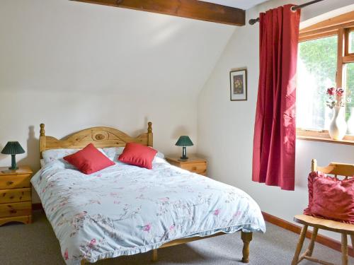a bedroom with a bed with red pillows and a window at Violets in Tonbridge